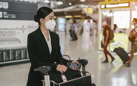 women withher luggage and trolley is wearing medical face masks to protect themselves from pollution, germs and coronavirus at the airport.