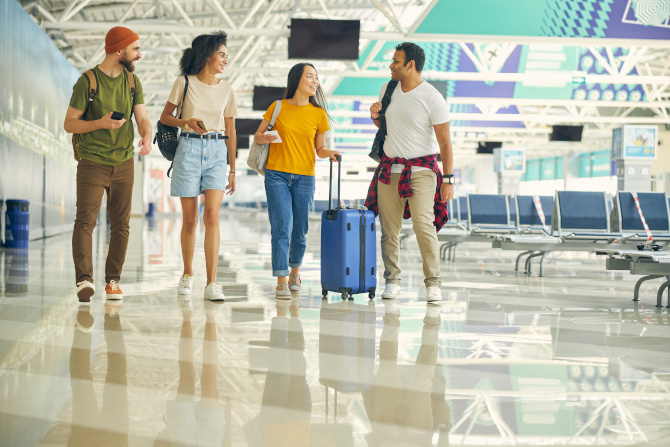 Happy team with luggage talking together while walking on the hall of modern airport