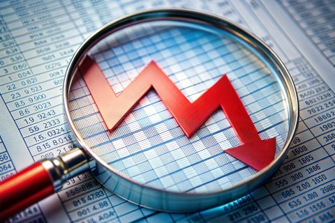 Magnifying glass on downward spreadsheet financial decline during business recession
